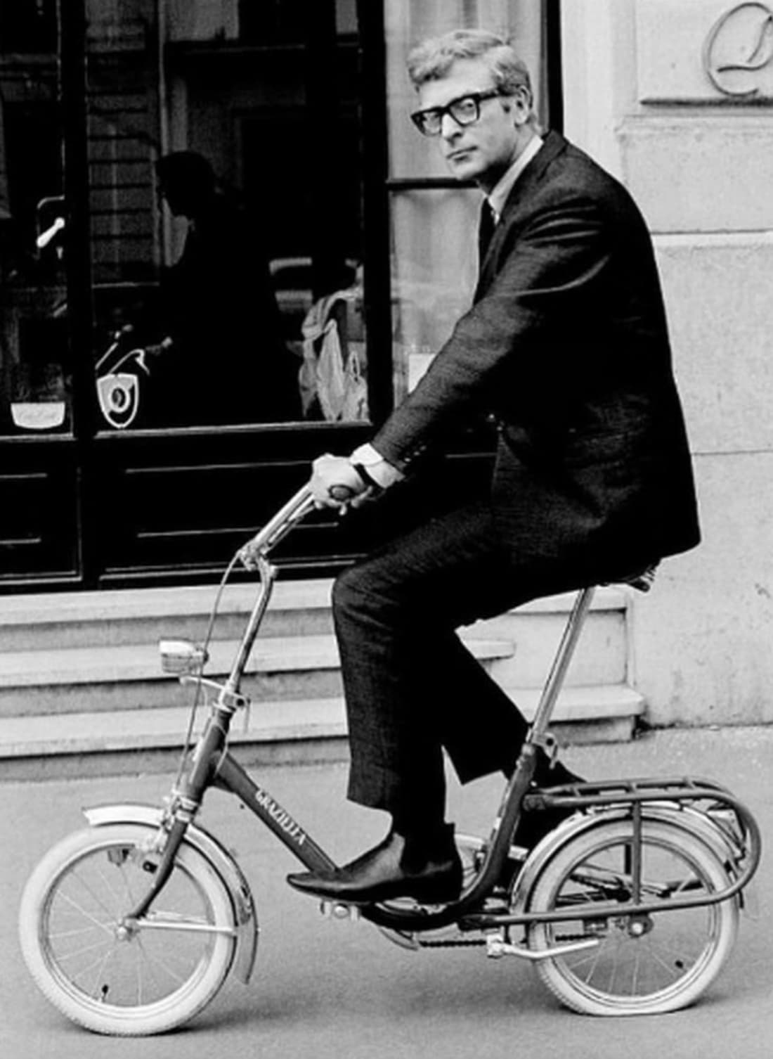 “Michael Caine riding a Graziella folding bike in Paris in 1966.”